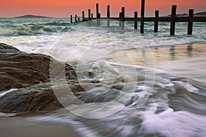 Rocks on the beach and wooden pier