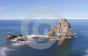 Rocks in the blue waters of the cantabric sea, pendueles beach in Asturias.