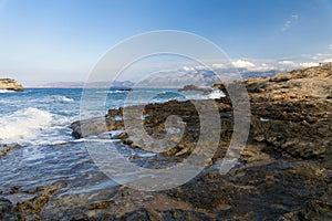 The rocks are in contact with the sea. Rocky beach, sharp rocks touching the sea, Greece island of Crete.