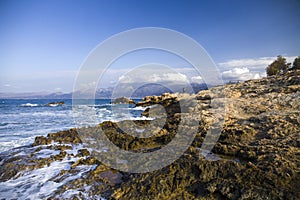 The rocks are in contact with the sea. Rocky beach, sharp rocks touching the sea, Greece island of Crete.