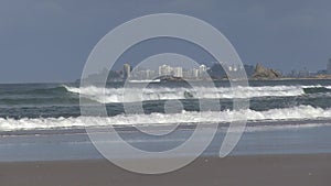 Rocks of Currumbin headland, with Coolangatta behind, visible from Palm Beach, Gold Coast, Australia.