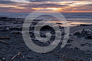 Rocks and driftwood on the beach at sunset near Yachats, Oregon, USA