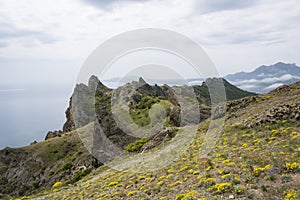 The rocks of the Kara-Dag mountain range against the sea and cloudy sky on the Crimean Peninsula