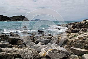 Rocks at Praia das Conchas, with blue sea and mountains in the background.