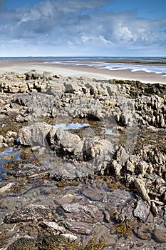 Rocas sobre el arenoso Playa a cielo azul nubes 