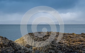 Rocks, sea and sailing boat scottish landscape