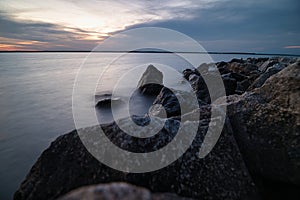 rocks are on the shore at sunset on a clear day