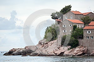 Rocks on shore and stone houses of Sveti Stefan island and hotel. Balkans, Adriatic sea, Montenegro, Europe