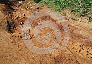 ROCKS AND SLOPPY MUD IN AN ERODED HOLLOW IN A DIRT ROAD AFTER RAINFALL