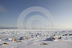 Rocks in the snow under a blue sky in the arctic, north of Arviat