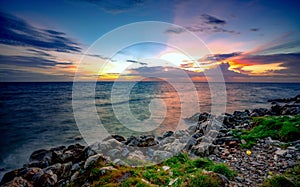 Rocks on stone beach at sunset. Beautiful beach sunset sky. Twilight sea and sky. Tropical sea at dusk. Dramatic sky and clouds.