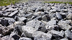 Rocks and stones on the road between the grass.