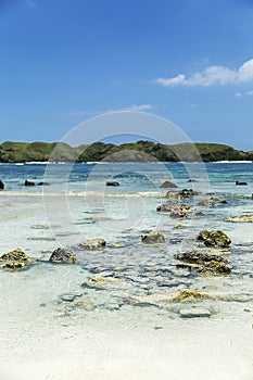 Rocks in a transparente light blue sea and mountains at the background photo