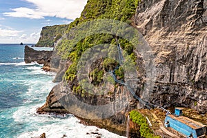 Rocks tropical vegetation, foamy ocean. Platform with stairs leading up. Klungkung Bali Indonesia