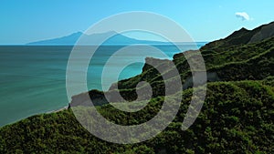 Rocks of an uninhabited island in the Mediterranean Sea. Clip. Forested green hills and blue sea with cloudless horizon