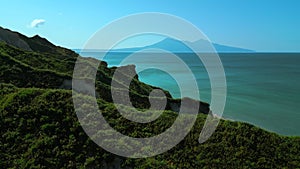 Rocks of an uninhabited island in the Mediterranean Sea. Clip. Forested green hills and blue sea with cloudless horizon