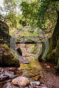 Rocks and water of Barroca de DegraÃÂ­nhos in lowlight with wooden foot bridge in Fraga da Pena, Arganil PORTUGAL photo