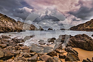 rocks and water on the beach in front of cloudy skies