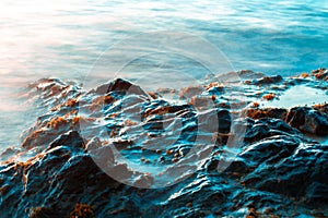 Rocks on a wavy sea in the sunset