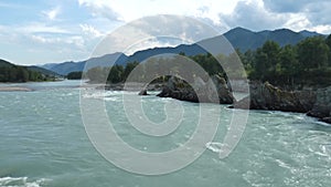 Rocks in wild mountain river. Fast water stream, hills and