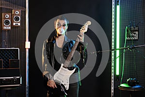 Rockstar guitarist holding electric guitar while playing rock music in sound studio