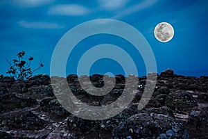 Rocky against blue sky and beautiful full moon at night. Outdoor