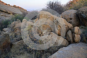 Rocky arid terrain with large boulders between rocky hills under a blue sky