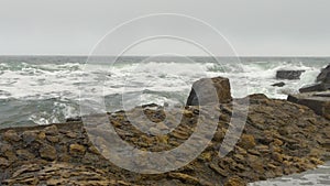 Rocky beach with choppy rough sea, yellow rocks, dense gray clouds covering sky.
