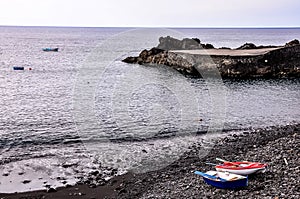 A rocky beach with a few boats on it