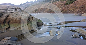 A rocky beach with a large rock in the middle