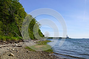 Rocky beach lined with trees on Cousins Island with Large Gas Po