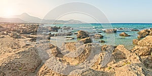 Rocky beach with mountains at background at sunrise