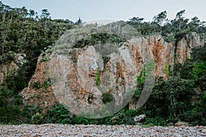 Rocky beach with red interesting geology and mediterranean vegetation, remote place