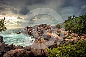 Rocky beach sea lagoon tropical scenery with palm trees and round stones with dramatic sunset sky vibrant colors in Sri Lanka