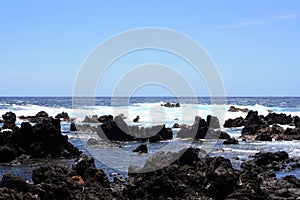 Rocky, black lava rock shoreline fronting deep blue Pacific Ocean at Laupahoehoe Point in Hawaii