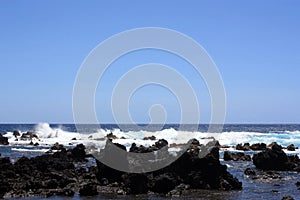 Rocky, black lava shoreline fronting deep blue Pacific Ocean at Laupahoehoe Point in Hawaii