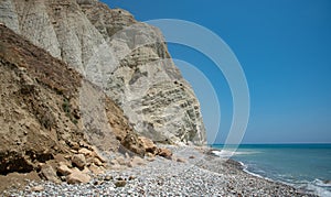 Rocky cliff in the ocean. A long and narrow stretch beach with a rocky shoreline