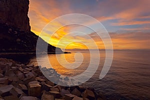 Rocky cliff surrounded by Mediterranean Sea during sunrise. Calpe, Spain