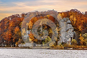 Rocky cliff with yellowed trees and mountain river in autumn