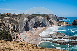 Rocky cliffs and silhouettes of people on the sand of Alteirinhos beach, Zambujeira do Mar - Odemira PORTUGAL photo