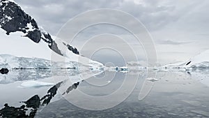 the rocky coast of Antarctica, clear water, A huge high breakaway glacier is passing by in the southern ocean off the