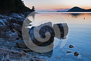 Rocky coast and calm water of Panormos bay after sunset, Skopelos island