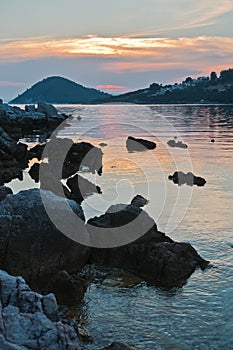 Rocky coast and calm water of Panormos bay at sunset, Skopelos island