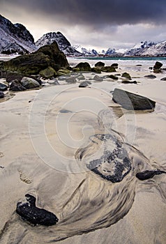 Rocky coast of fjord of Norwegian sea in winter with snow. Haukland beach, Lofoten islands, Norway.