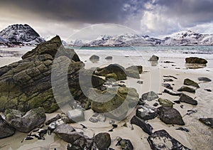 Rocky coast of fjord of Norwegian sea in winter with snow. Haukland beach, Lofoten islands, Norway.