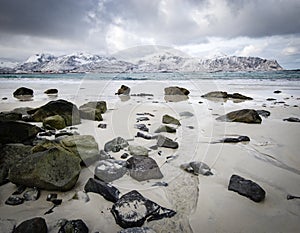 Rocky coast of fjord of Norwegian sea in winter with snow. Haukland beach, Lofoten islands, Norway.