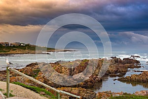 Rocky coast line on the ocean at De Kelders, South Africa, famous for whale watching. Winter season, cloudy and dramatic sky.