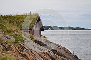 Rocky coast of Norwegian sea with the traditional Scandinavian turf roof construction in the background