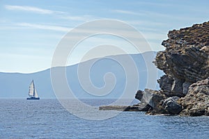 Rocky coast and a sailing catamaran at the background