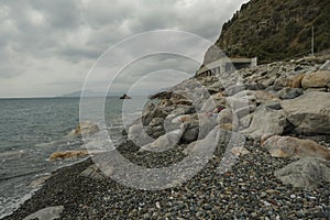 Rocky coast of the sea, tunnel in the mountains across the sea horizon, mountains and dramatic sky.  Scenic landscape. Sestri Leva